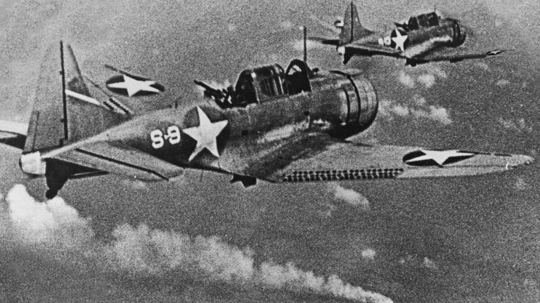 1942년 6월 6일 미드웨이 해전 중 불타는 일본 순양함 미쿠마 상공을 지나는 미 해군 SBD-3 던틀리스 급강하폭격기 편대