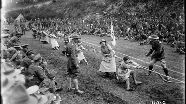 1918년 야외 행사에서 여러 사람이 한 줄에 매달려 줄다리기를 하는 흑백 사진